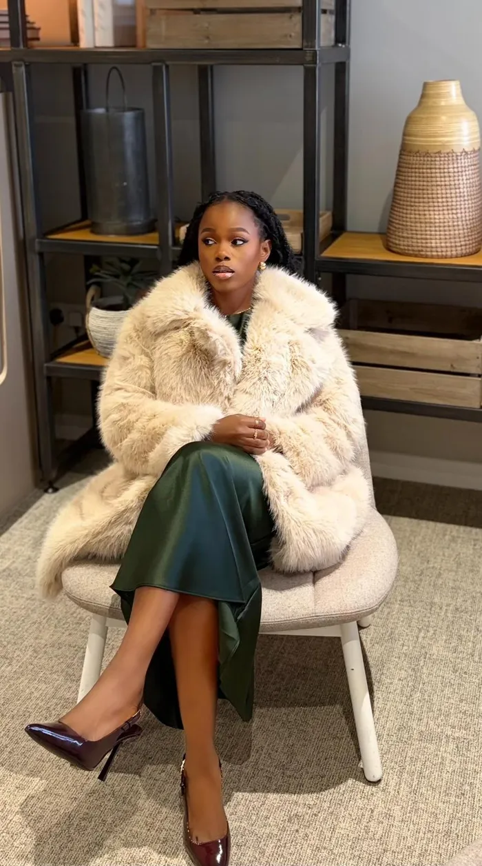 Precious seated in a cream jacket and green skirt