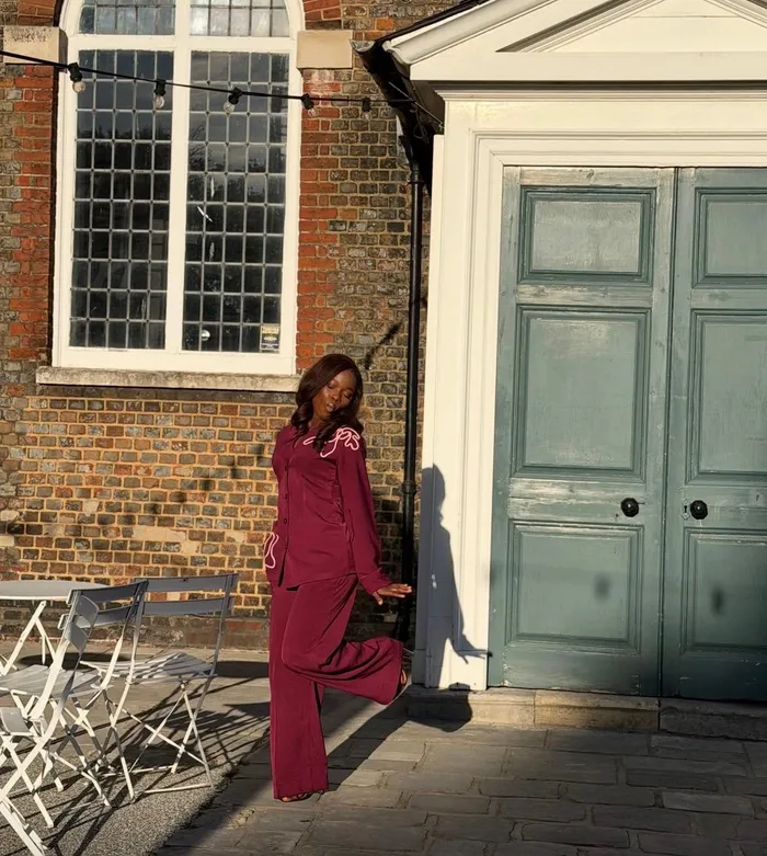 Precious in burgundy beside a pale doorway